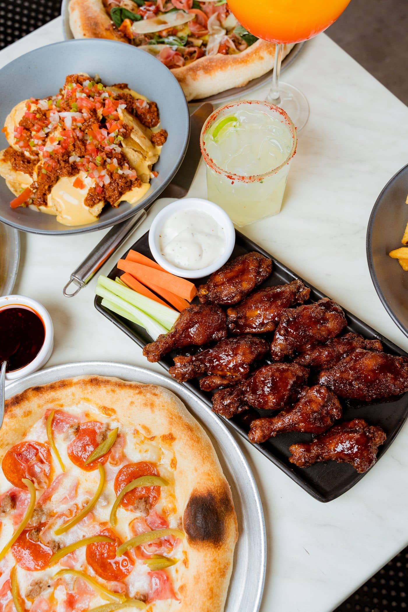 Mesa con pizza, alitas, nachos y bebida