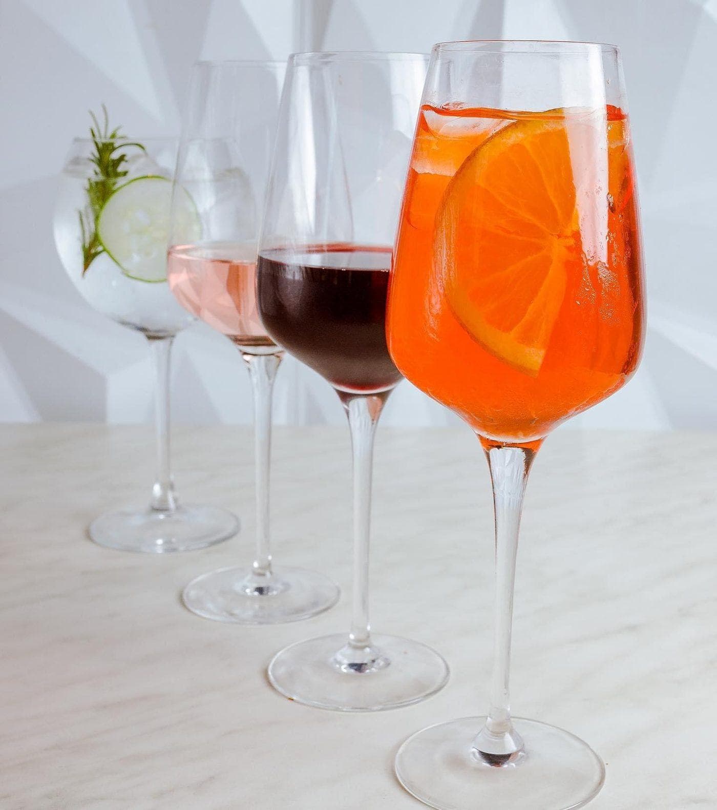 Cuatro copas de la barra de Peccati, con un spritz de naranja al frente